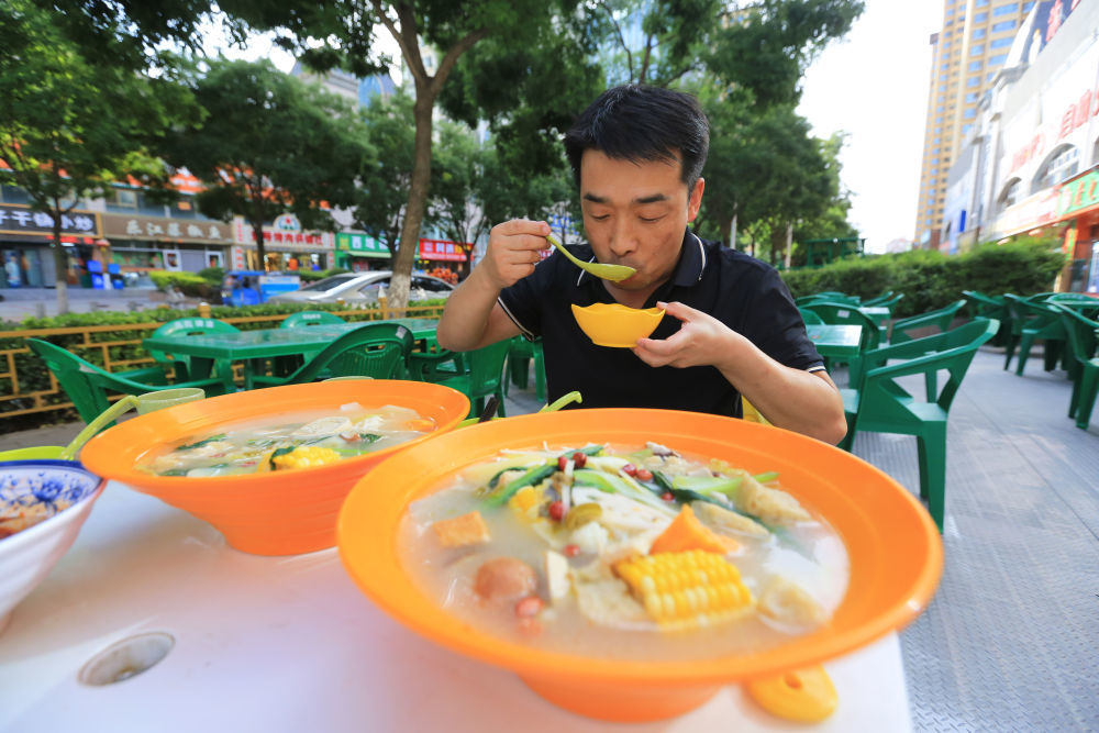 7月17日,顾客在甘肃省定西市安定区一家餐馆品尝浆水麻辣烫。新华社发(王克贤 摄)