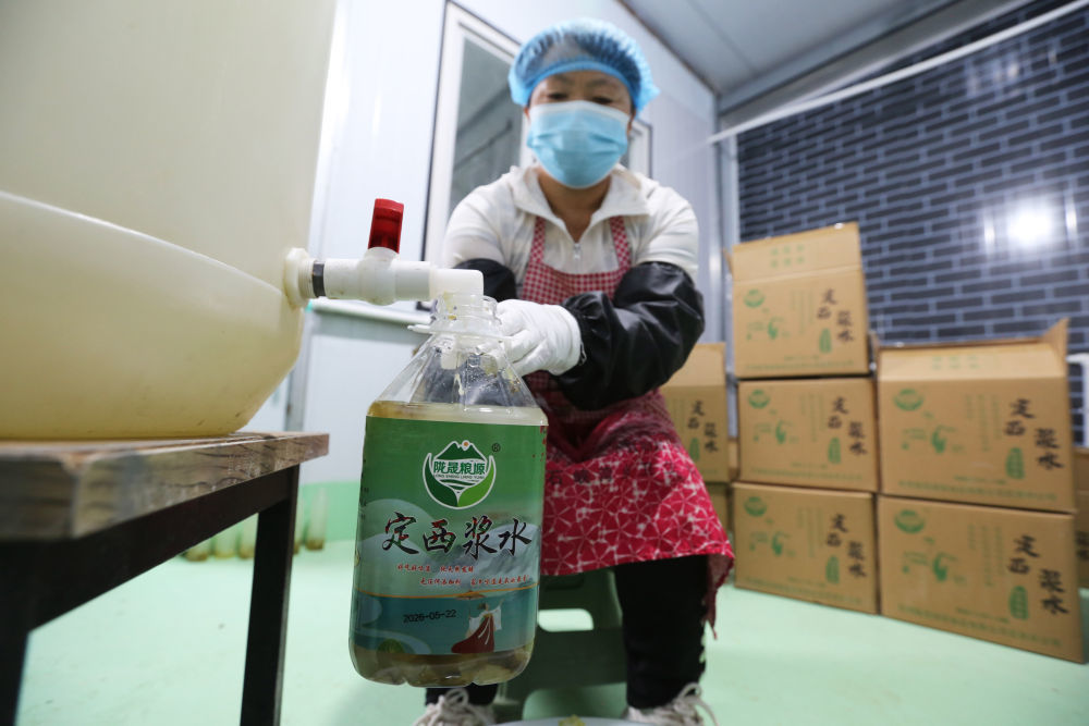 7月10日,甘肃省定西市安定区石峡湾乡一家合作社的工人在灌装浆水。新华社发(王克贤 摄)