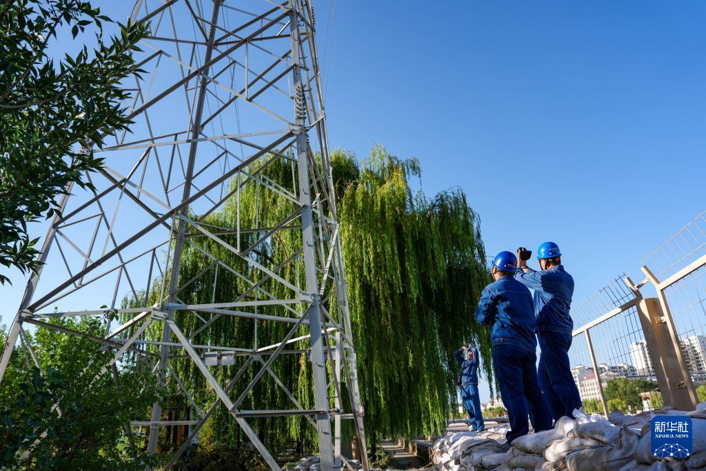 7月30日,在敦煌市党河岸边,电力工作人员对重要输电线路开展特巡特护作业。新华社记者 郎兵兵 摄