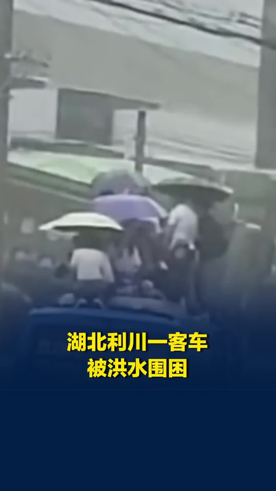 湖北利川一客车被洪水围困，十余人爬上车顶，当地用装载机救人