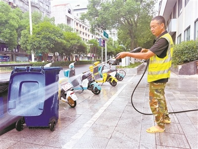 市区解放路上，环卫工人手持高压水枪冲洗街边垃圾桶，对环境设施进行精细化保洁。马欣然摄
