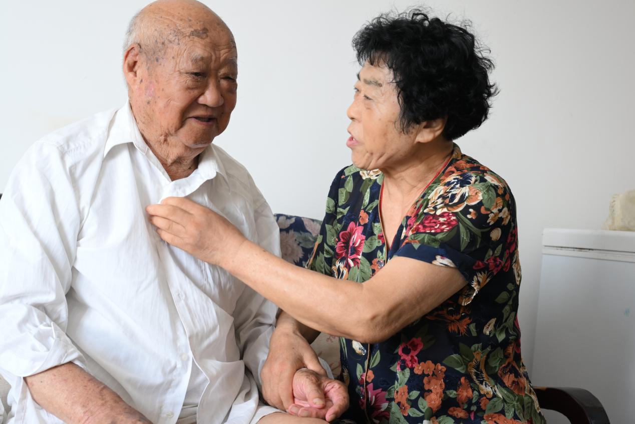 7月30日，王翠珍给92岁的抗美援朝老兵王永昌整理刚换洗的新衬衫。