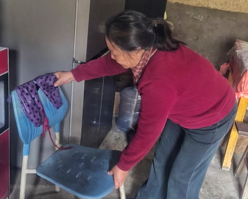 胡军秀帮助村里老人打扫屋子