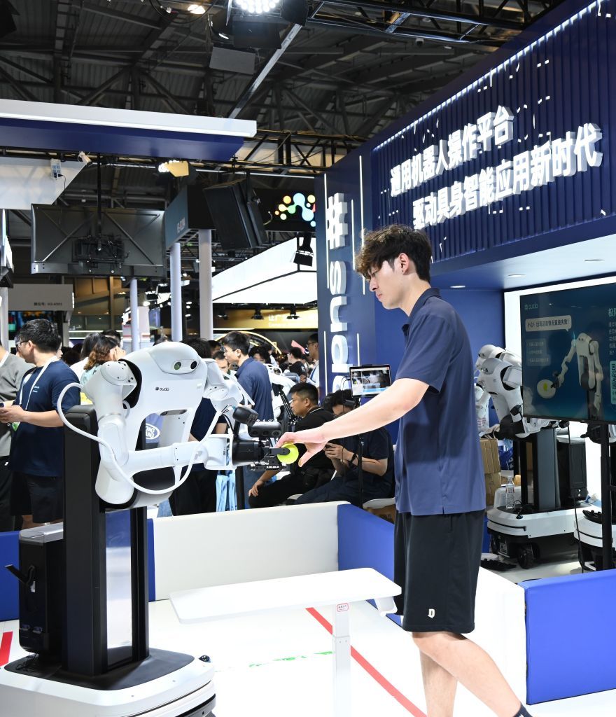 7月19日,在2026世界人工智能大会上,一台机器人从工作人员手中接过物品。新华社记者黄晓勇 摄