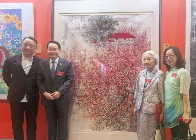 萧晖荣教授与知名人士梁爱诗(右二)在《红岩精神》作品前合影,子女萧扬、萧芬琪陪伴
