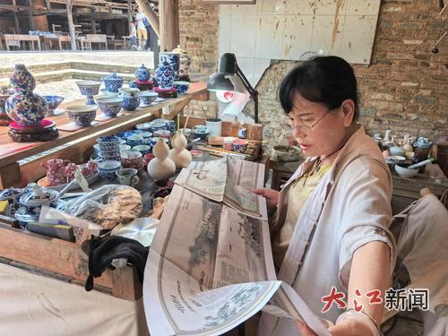 一名景德镇摊主认真看江南都市报特刊