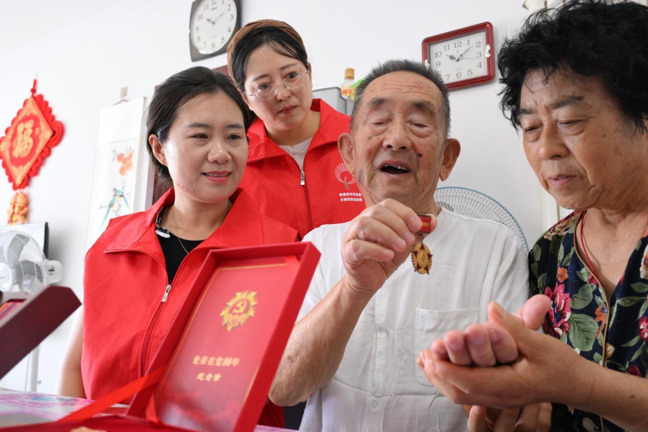 7月30日，94岁的抗美援朝老兵周正本在家里为王翠珍和志愿者们讲述抗美援朝奖章的故事。