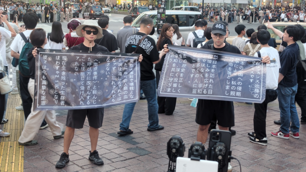 法国后生马库斯（右）和中国后生钟灏松5日在日本东京街头手举口号，敦促日本社会正视历史，遵从和平。 刘文璋摄