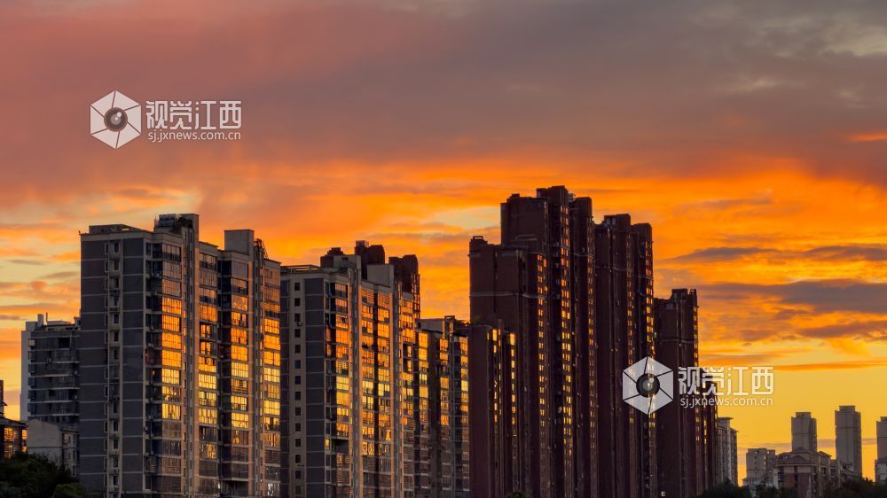 落日余晖映照高楼,楼宇窗户泛着暖金色光芒,浓艳云霞与城市建筑相融,展现风雨前夕的都市暮色。