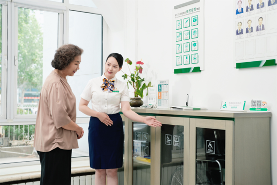 图:柜面服务人员为老年客户介绍适老化服务设施