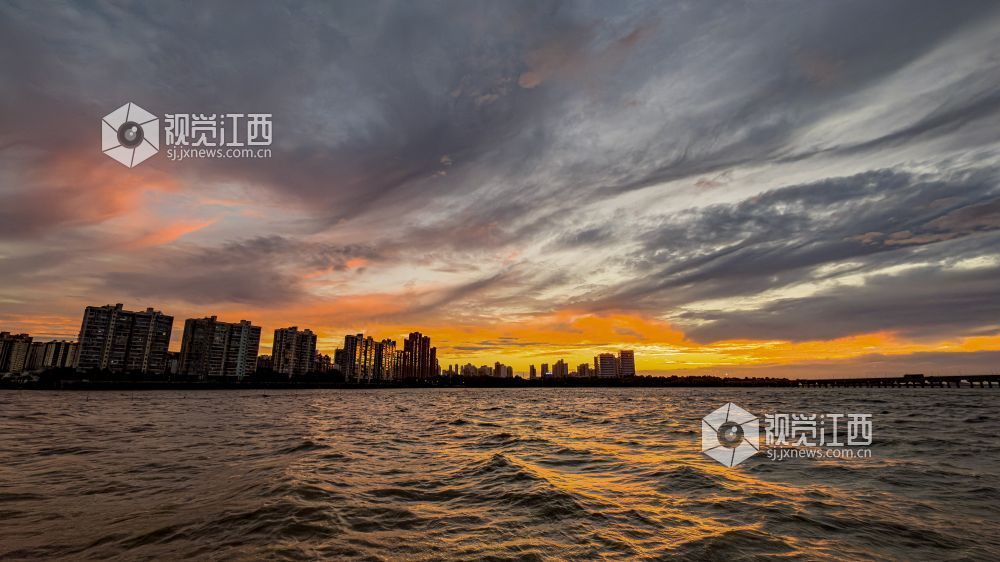 台风 “白海豚” 来临前夕,湖面水波翻涌,漫天彤云纵横交织。落日铺洒橙金霞光,临湖城市静立水岸,定格风雨将至、蓄势待发的独特景象。