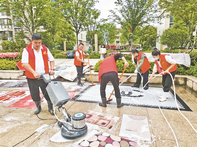 党员志愿者与红色管家为居民清洗地垫。