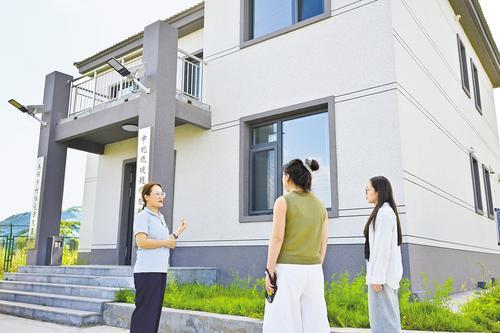 8月14日,在中规低碳(张家口)建筑技术有限公司的样板房外,工作人员向客商介绍被动式超低能耗建筑的优势。本报记者 郭晓通摄