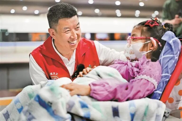志愿者在深圳北站接患病儿童到医院就医。