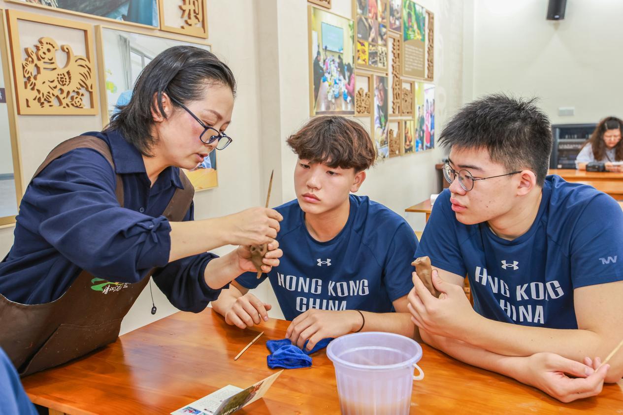 图为中国香港男子U16三人篮球队球员体验靖江泥哨制作。