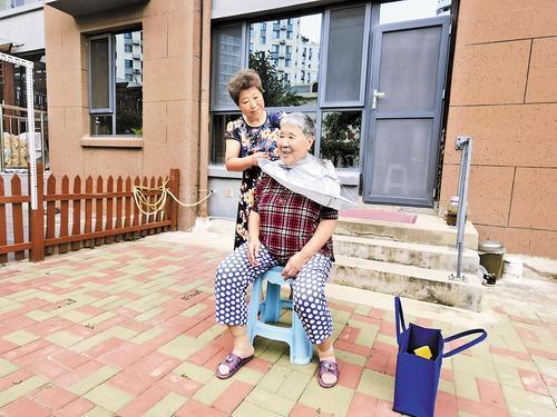 8月20日，左岸社区志愿者王春艳（后）来到王桂芝家，义务为其理发。本报记者 孙也达摄