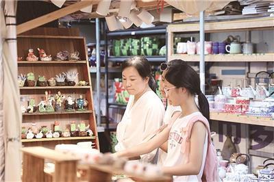 家长和孩子在雕塑瓷厂步行街选购陶瓷小摆件。 (全媒体记者 余乐俭 摄)