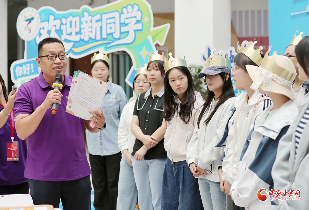 老师将去年新生集体生日会上学长学姐写的一封书信,郑重地交到新同学手中。