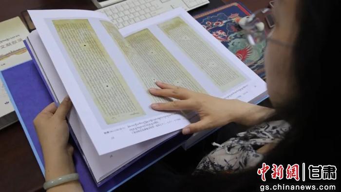 图为敦煌研究院服务中心工作人员查看文献 酒泉市融媒体中心供图