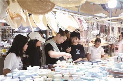陶源谷摊玩集市内,来景研学的学子正在参观选购心仪的茶杯。 (全媒体记者 余乐俭 摄)