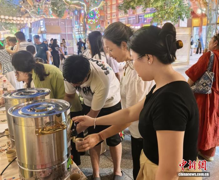7月21日夜晚，游客在敦煌健康赶大集活动中品尝金银花养生茶饮。（敦煌市官方供图）