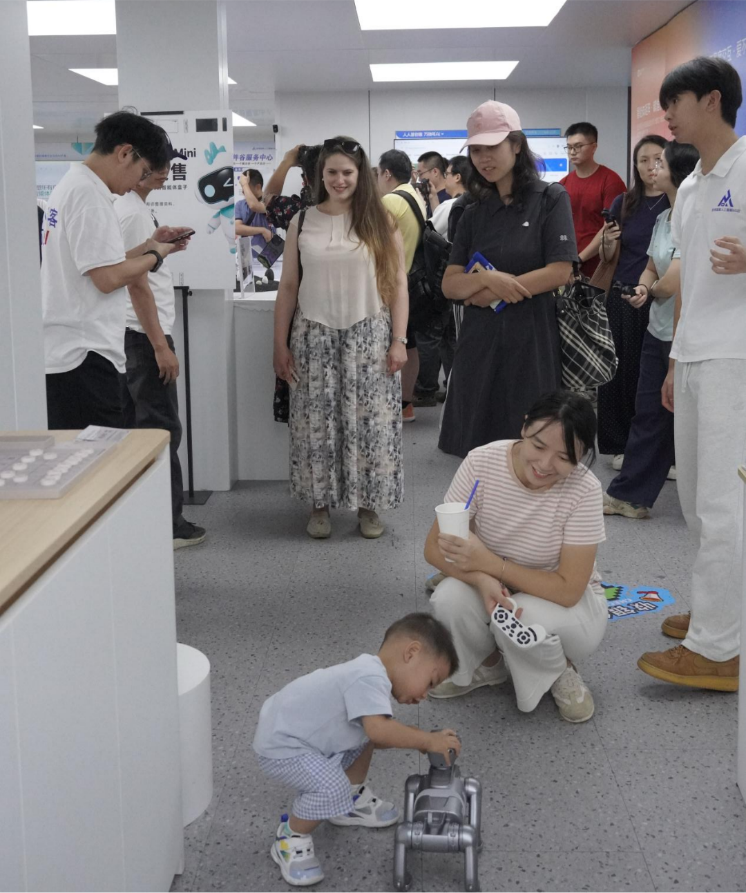 俄罗斯籍友人刘欢(Liuba)被小朋友玩机器狗的画面吸引住了。(叶惠玲 摄)