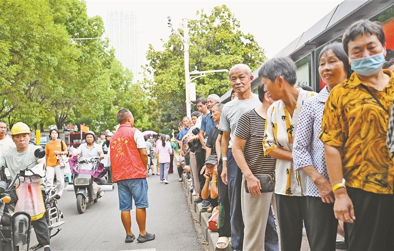 8月12日,戴西辉提醒前来领取爱心晚餐的病患及家属有序排队。