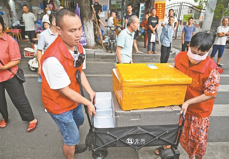 8月12日,戴西辉和志愿者一起将餐食搬运至派发地点。