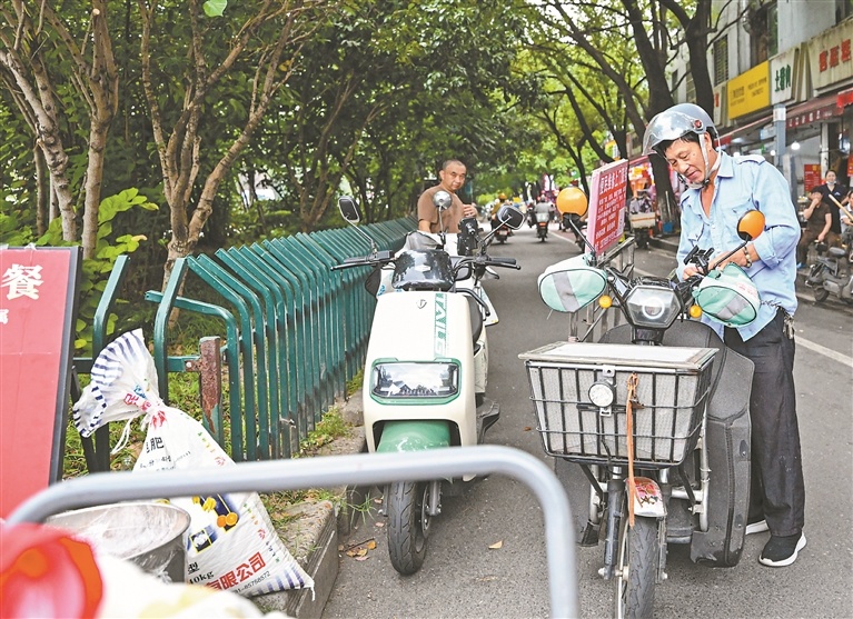 8月13日,一名务工人员将自家种植的大米送至爱心摊位。
