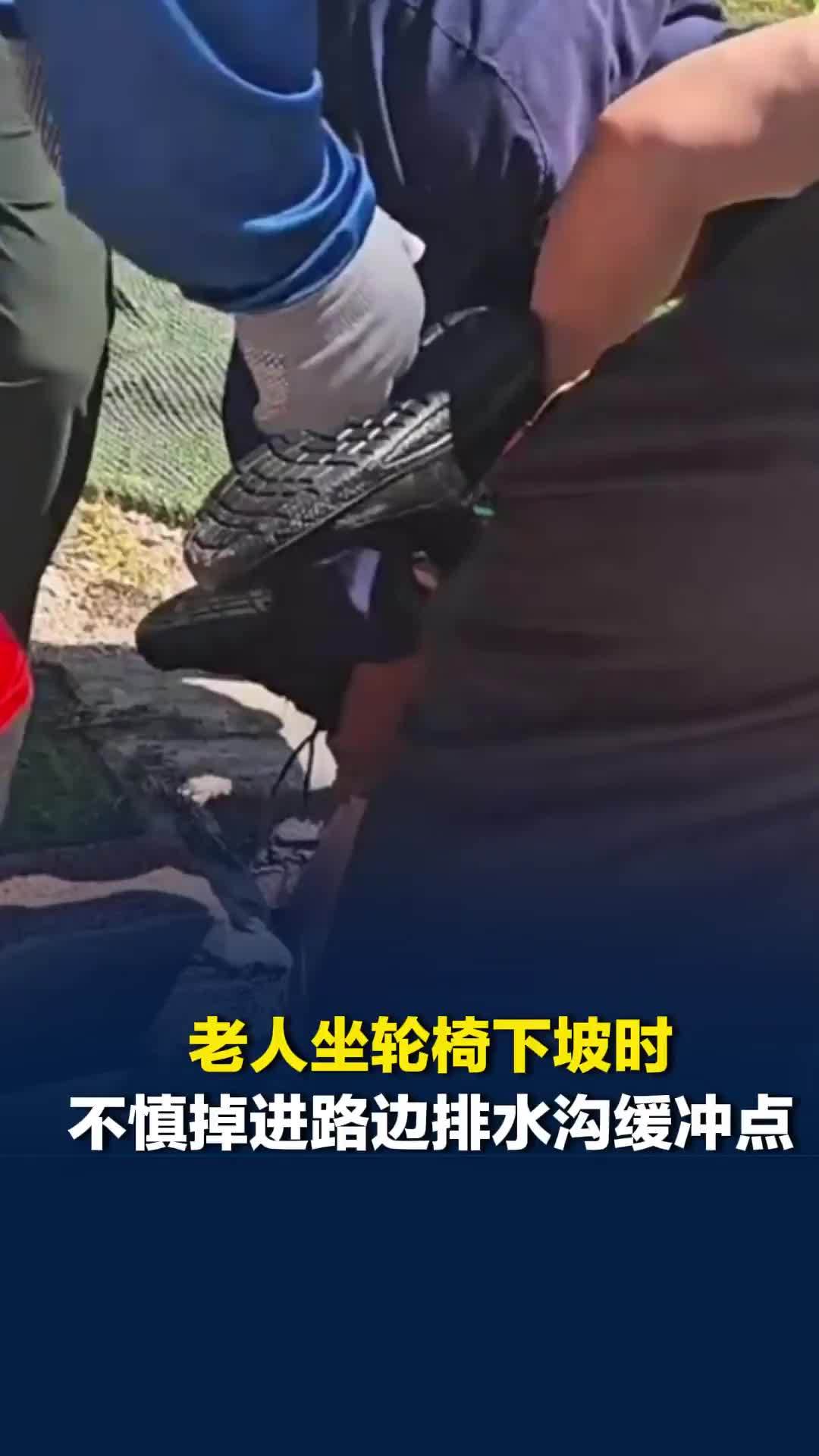 老人坐轮椅下坡时，不慎掉进路边排水沟缓冲点，附近热心群众纷纷赶来合力救人