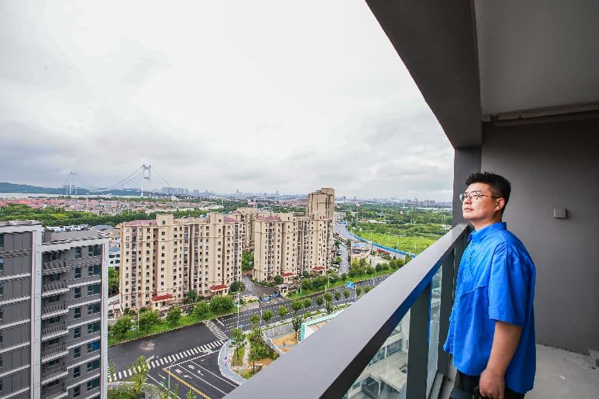 杨旭在新房阳台上看江景。盛义摄