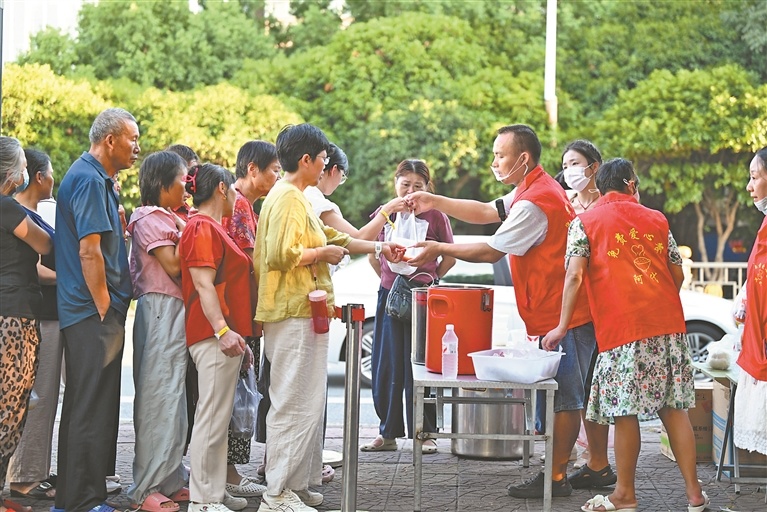 8月19日,江西省肿瘤医院南门附近,退役军人戴西辉正在为病患及其家属派发免费爱心晚餐。