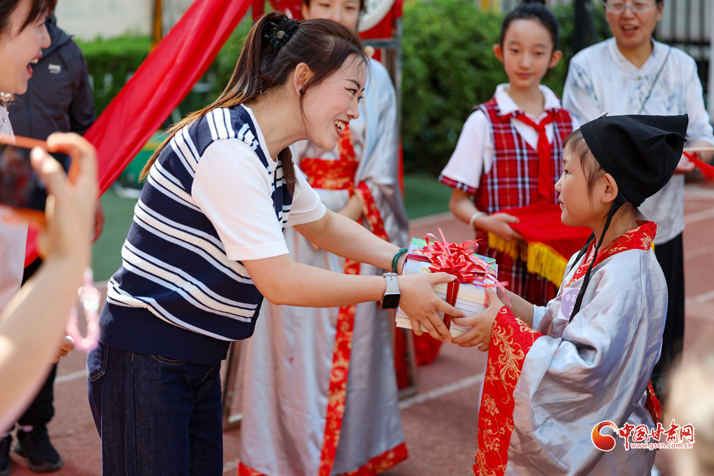 9月4日,在兰州市七里河区七里河小学“开笔礼”仪式上,老师为一年级新生赠送书籍。