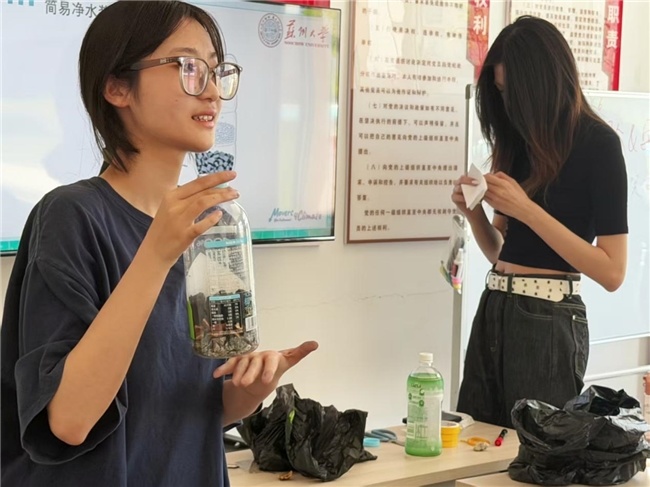 图为团队成员向孩子们展示净水装置示例成品
