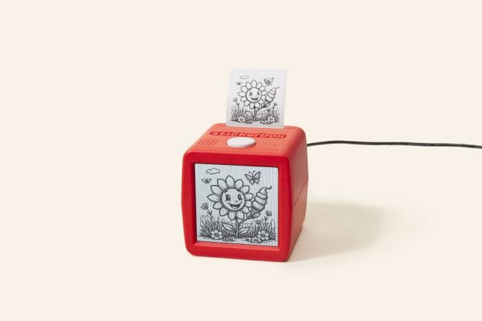 A red cube called Stickerbox, an AI-enabled toy, displaying and printing an illustration of a smiling sunflower with an ice cream cone.