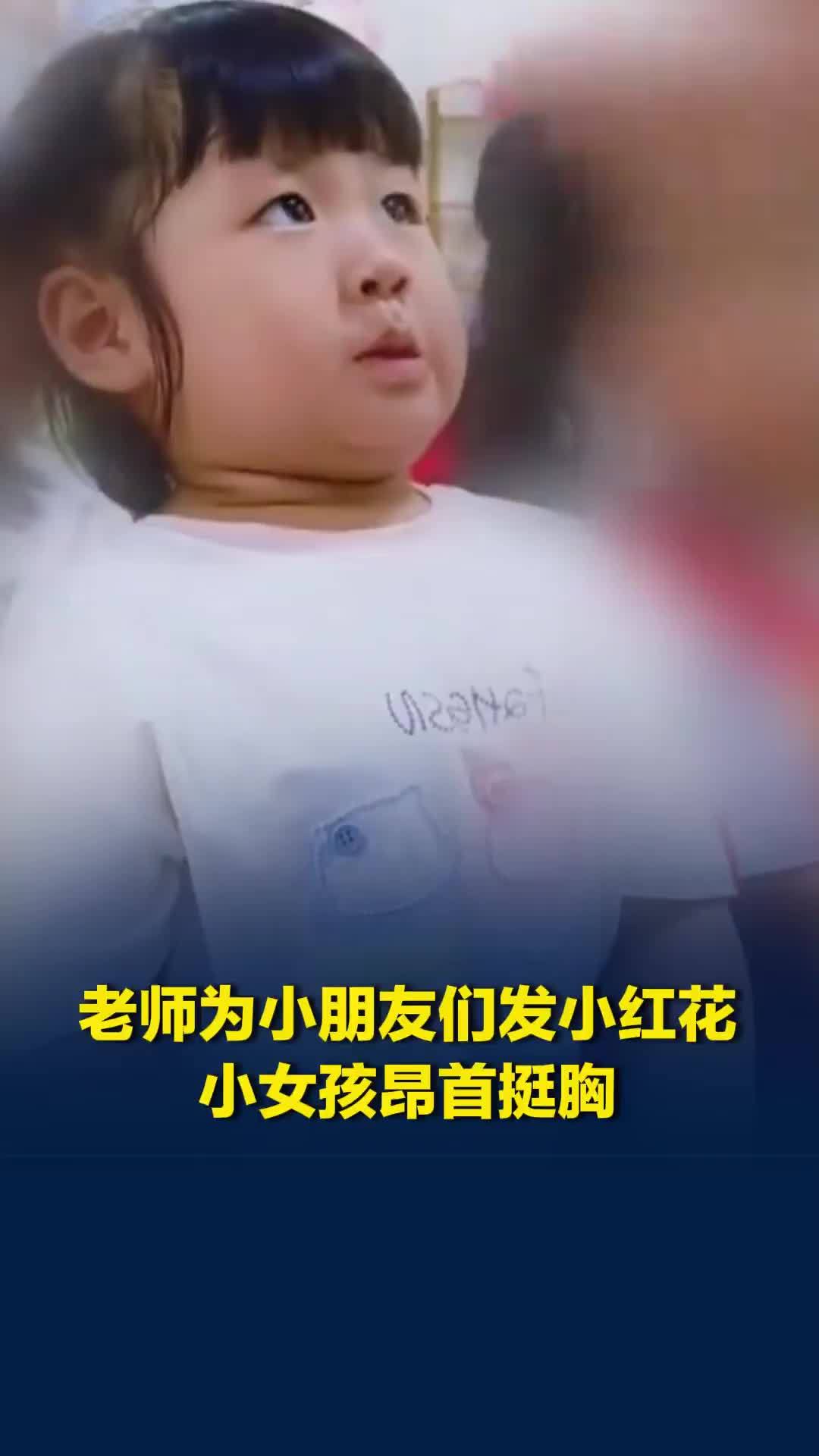 老师为小朋友们发小红花，小女孩昂首挺胸，满脸写着期待，网友：仪式感拿捏住了