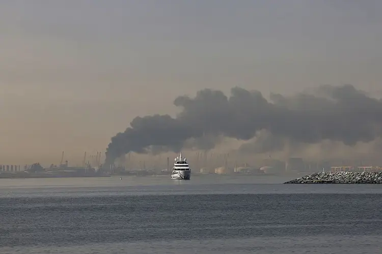 3月1日,伊朗对迪拜发动袭击后,一艘游艇驶过杰贝阿里港升起的浓烟。
