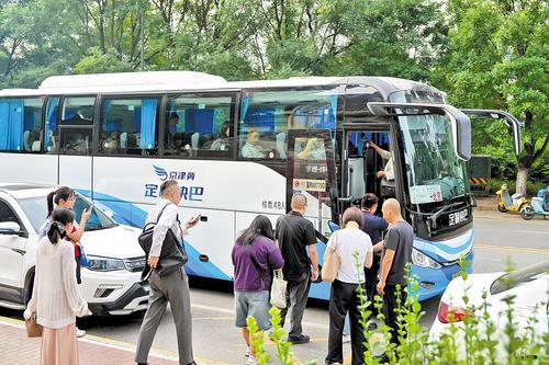 近日,在三河市燕郊镇燕京航城南门站点,乘客排队乘坐驶向北京的定制快巴。本报记者 王 伟摄