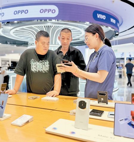 9月11日，信誉楼黄骅旗舰店华为手机柜组，导购员刘芮冰（右一）正为顾客介绍手机。本报记者 白云摄