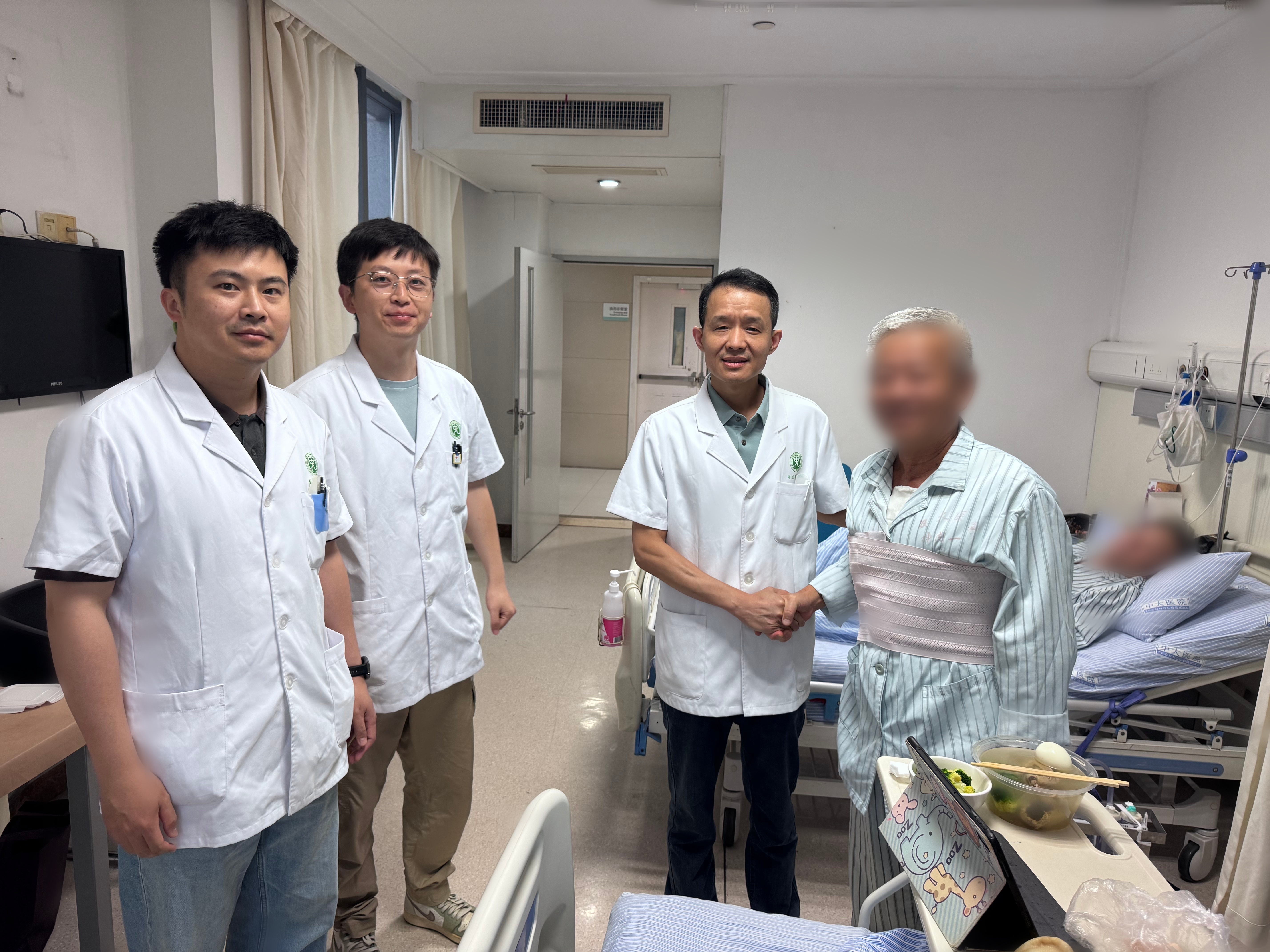 出院前,周建明副主任医师(右二)带领团队为李叔查房