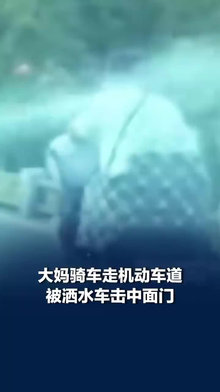 大妈骑车走机动车道被洒水车击中