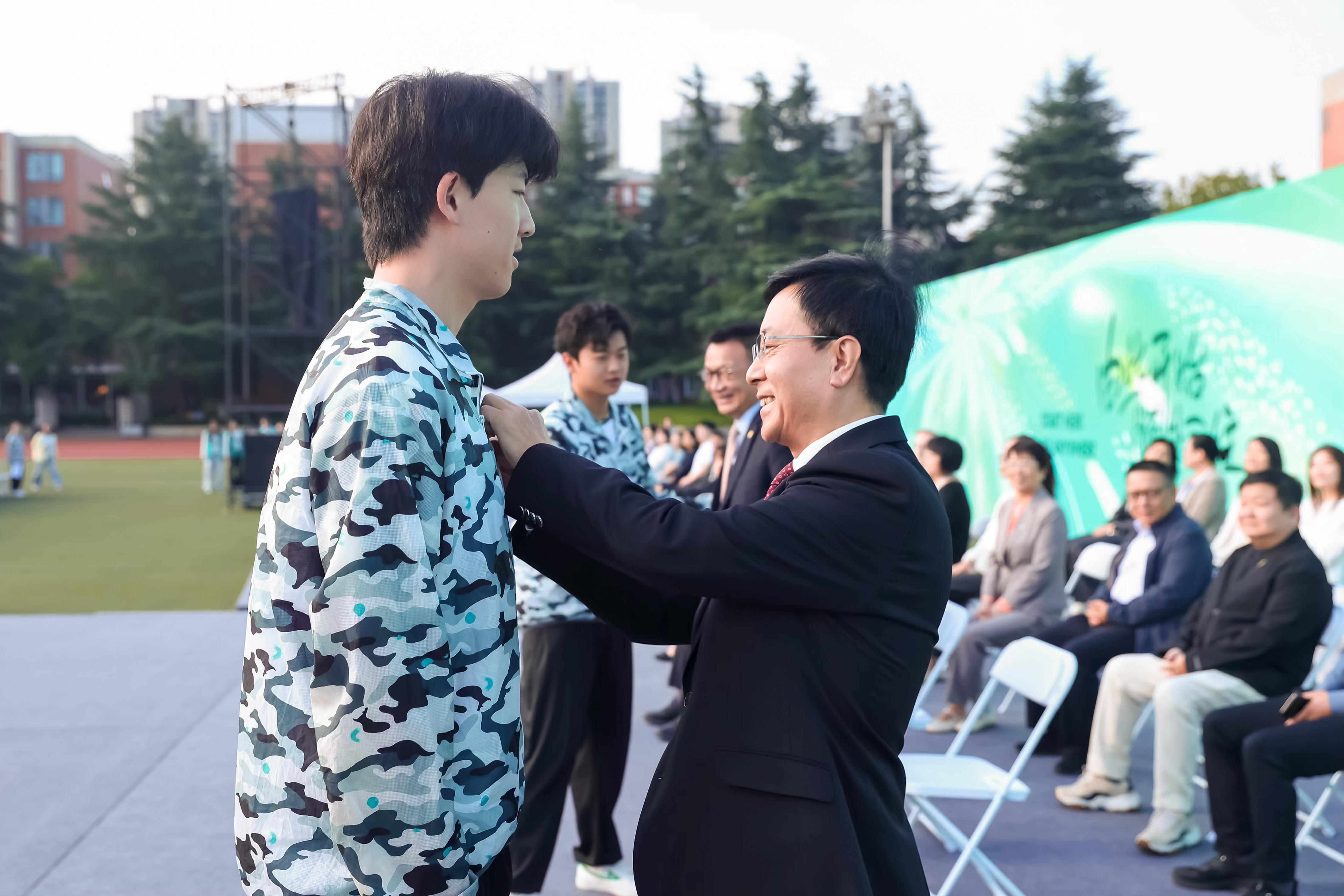 董事长胡建波教授（上），校党委书记赵国华（下）共同为新生佩戴校徽