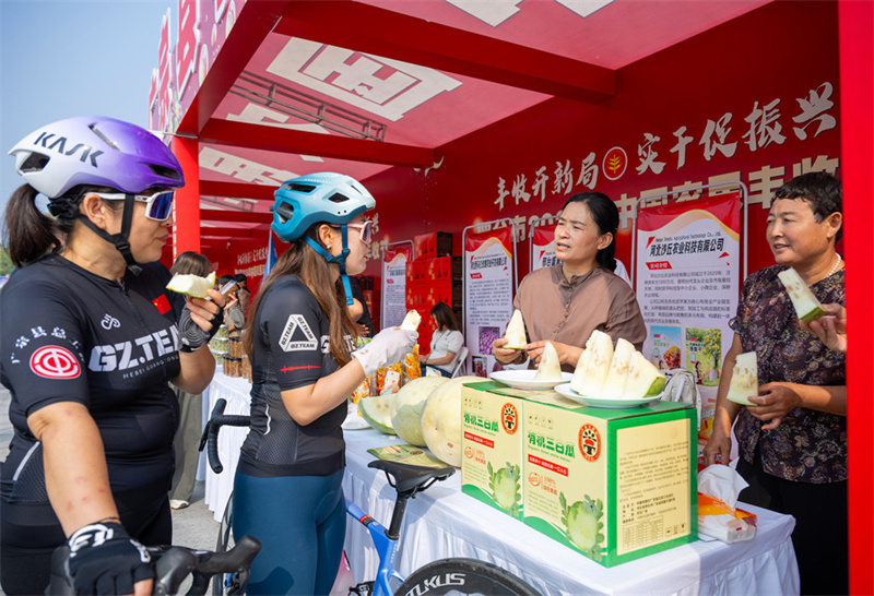 9月23日,自行车骑行爱好者在品尝广宗特色农产品三白瓜。