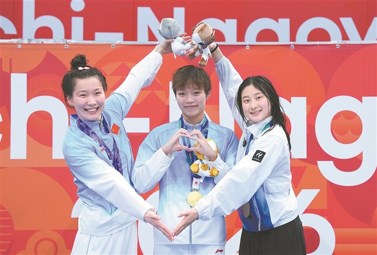 9月21日,冠军中国选手万乐天(中)、亚军中国选手汪雪儿(左)、季军韩国选手金承垣在颁奖仪式上。当地时间9月21日,爱知·名古屋亚运会游泳项目女子50米仰泳决赛在东京水上运动中心举行。新华社记者 陈泽国摄