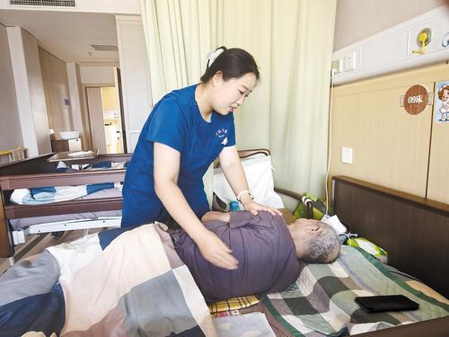 9月15日,照护师倪鑫茹为老人翻身拍背。本报记者 张辉摄