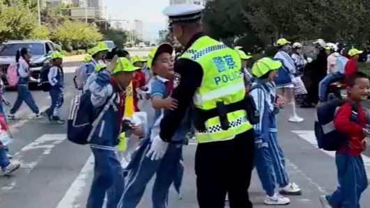 交警指挥过马路，被小朋友们要抱抱