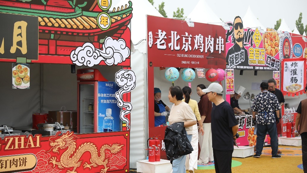 美食区摊位前，游客驻足选购小吃。