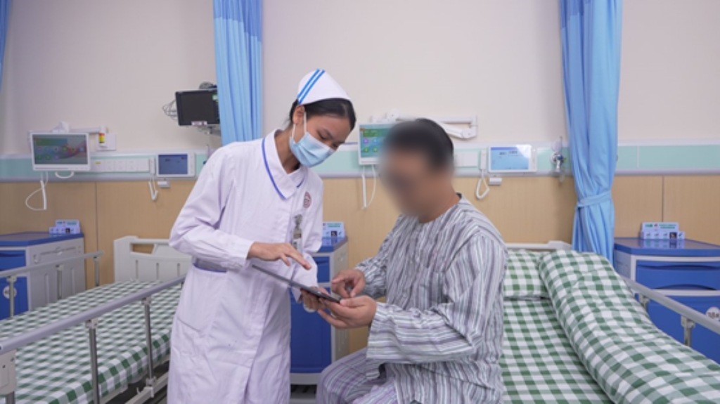 ▲护士持移动终端在患者床边沟通