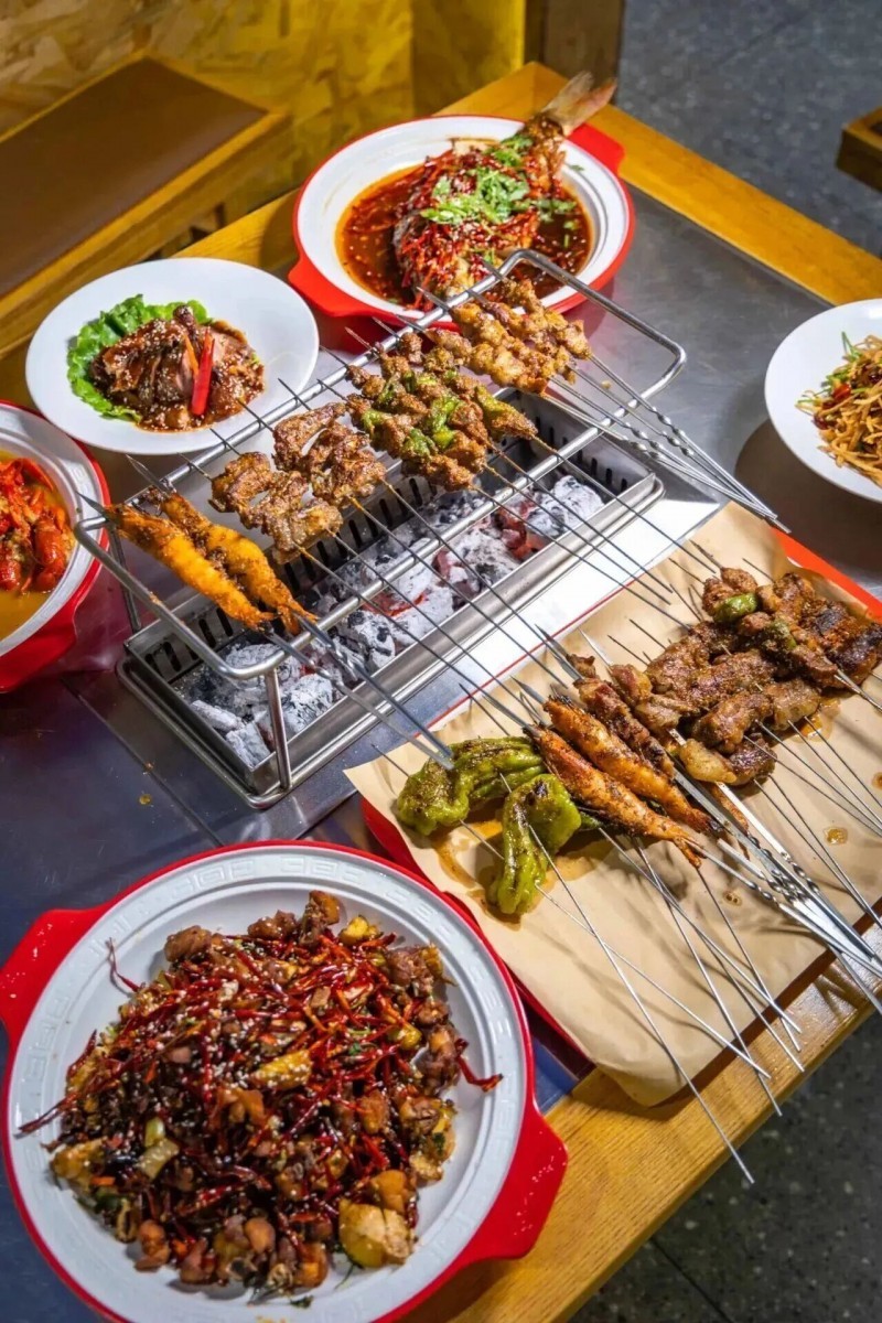 两千年后的街巷，傍晚时分，烧烤店炭火熊熊，各色食材在火上滋滋作响，三五好友围坐，香气漫过街巷。石头上的汉代宴饮图，化作了今夜鲜活的市井狂欢——原来两千年前先民们炙烤而食的，不只是一顿美味，更是对生活相聚的珍视。