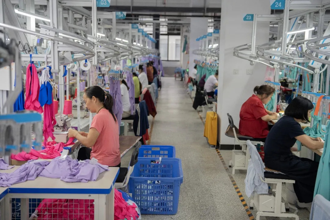 8月25日，益阳市湘银之舞服饰有限公司生产车间，工人在生产线上有序作业。湖南日报全媒体记者 李健 摄